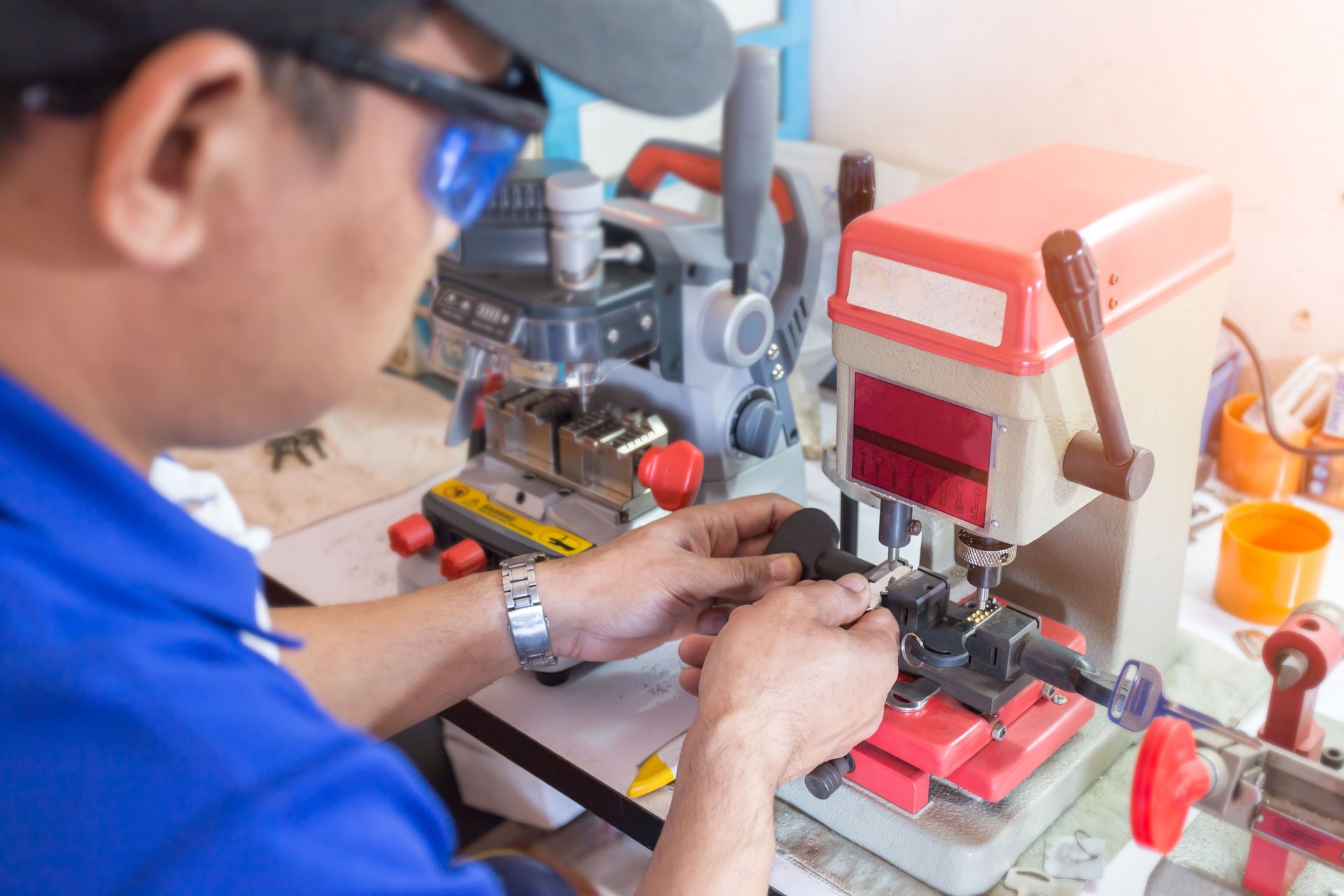 Locksmith in workshop makes new key. Professional making key in locksmith.